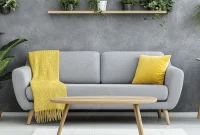 Interior ruang keluarga modern dengan furnitur minimalis, lantai kayu, dan jendela besar menghadap taman, calon pembeli duduk di sofa sambil mengecek smartphone