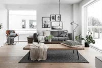 Interior rumah modern bergaya Skandinavia dengan sofa abu-abu, meja kayu, tanaman hias, dan pencahayaan hangat, menunjukkan kenyamanan yang menjadi nilai jual investasi properti