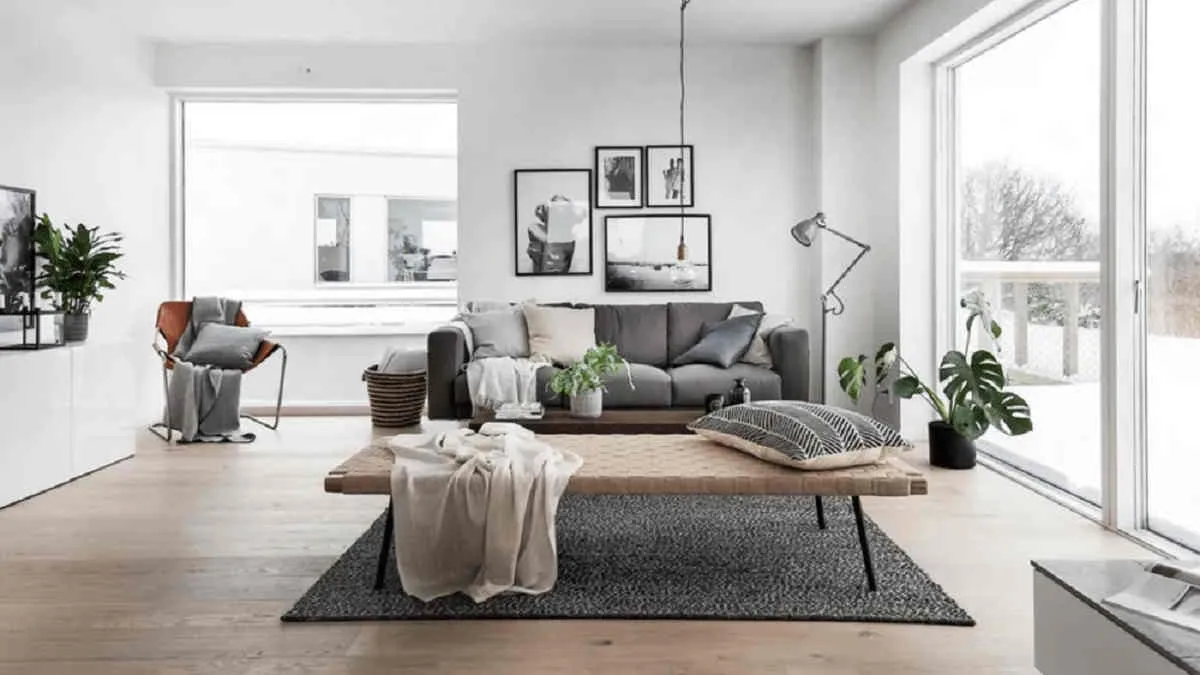 Interior rumah modern bergaya Skandinavia dengan sofa abu-abu, meja kayu, tanaman hias, dan pencahayaan hangat, menunjukkan kenyamanan yang menjadi nilai jual investasi properti