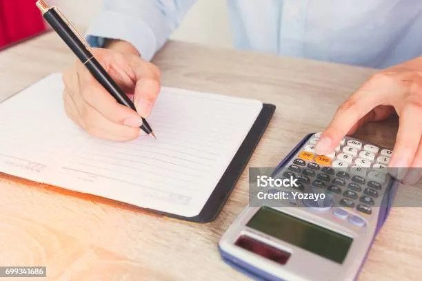 Orang menulis catatan keuangan di buku dengan pensil, kalkulator di samping